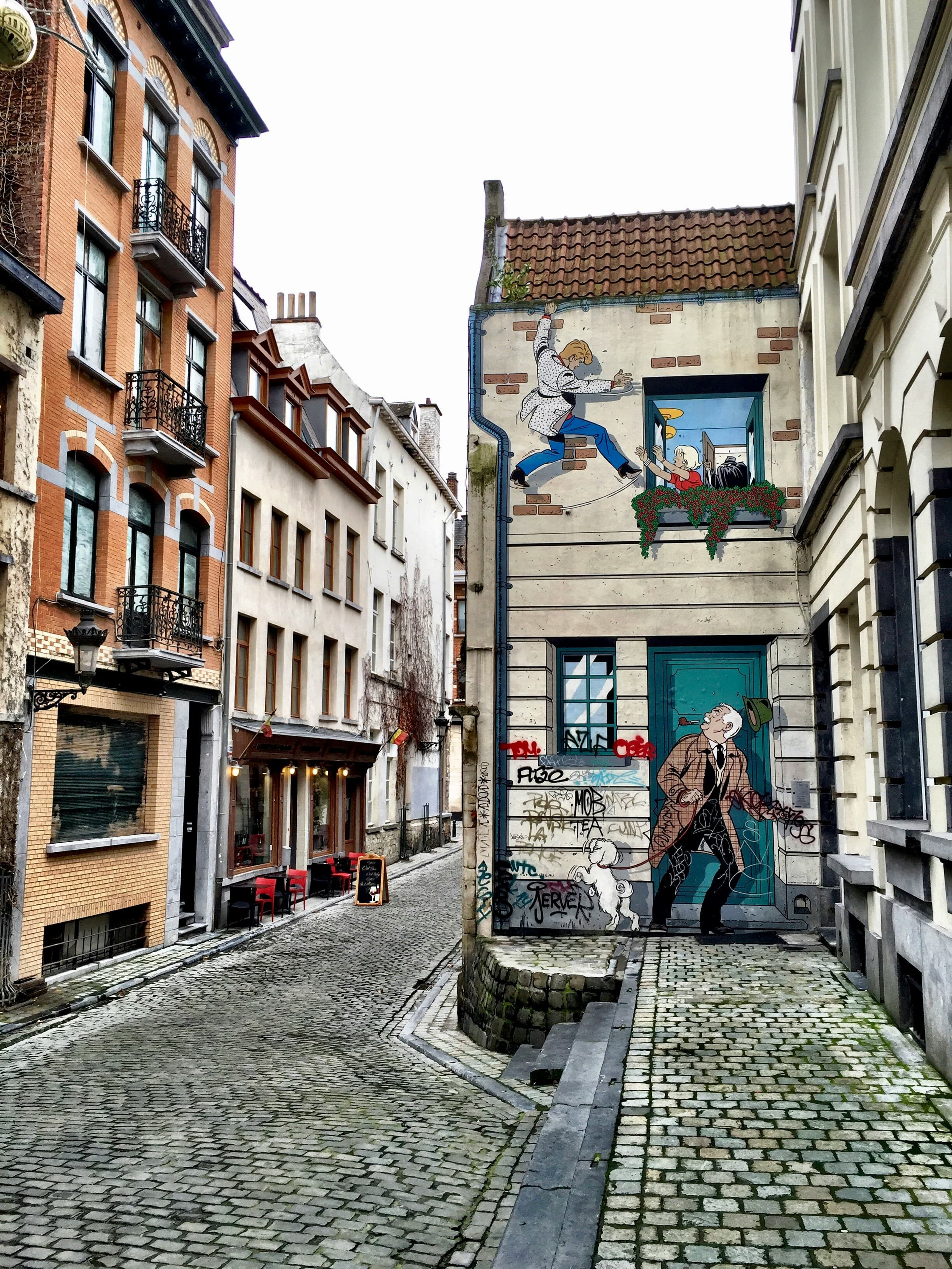 A cobblestone street with a Tintin comic mural on a building in Brussels, Belgium